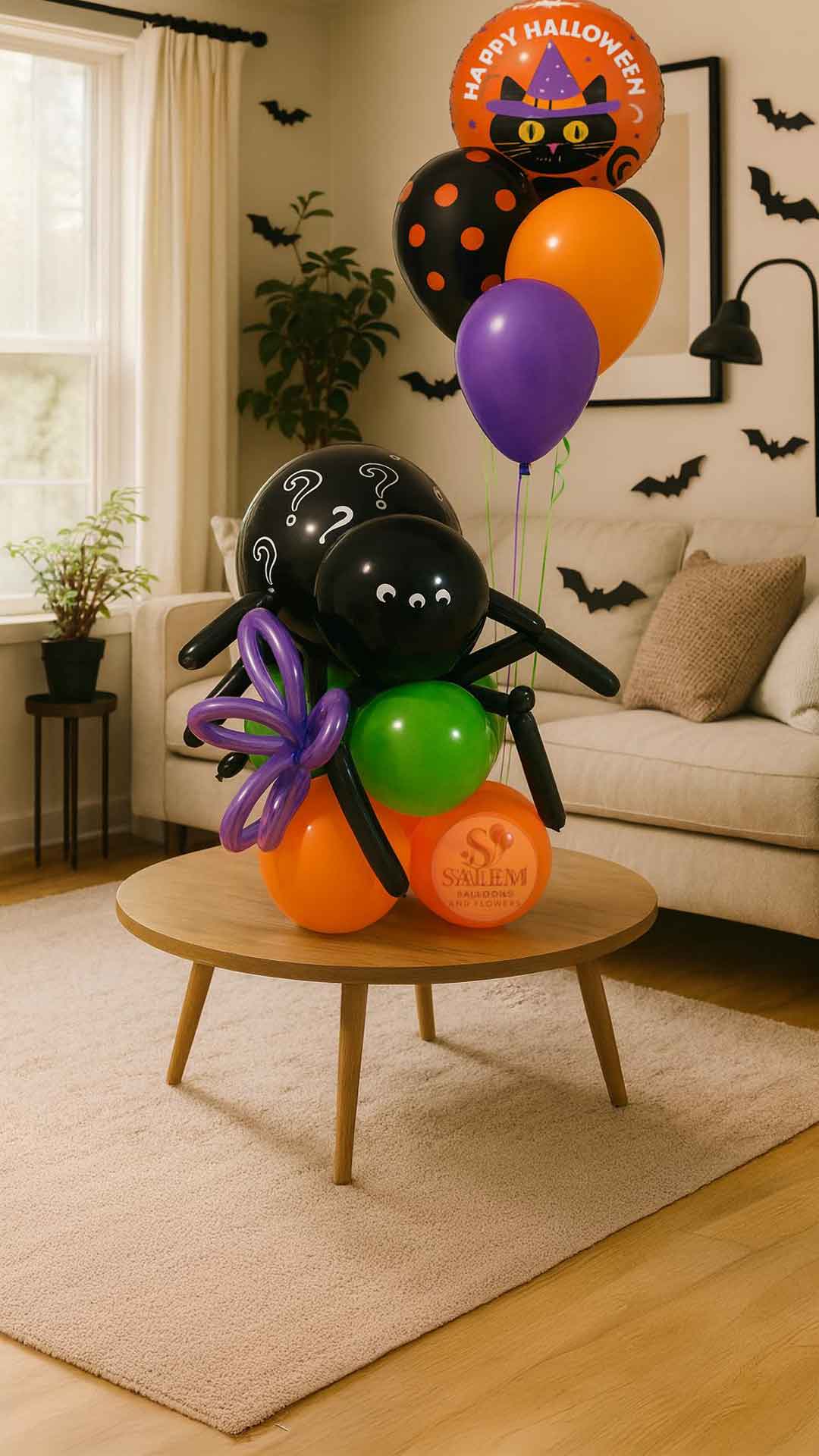 Halloween-themed balloon arrangement with spider and cat designs on a table in a living room. Balloon delivery Oregon.